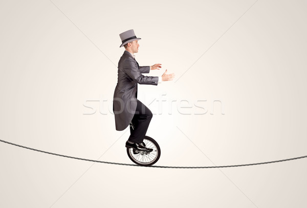 Extreme business man riding unicycle on a rope Stock photo © ra2studio