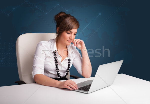 Stock photo: Young woman sitting at desk and typing on laptop