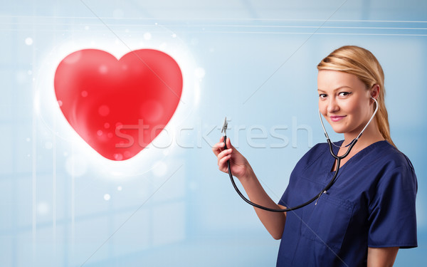 Young nurse healing a red heart Stock photo © ra2studio