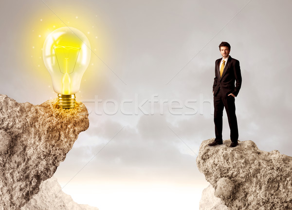 Businessman on rock mountain with idea bulb Stock photo © ra2studio