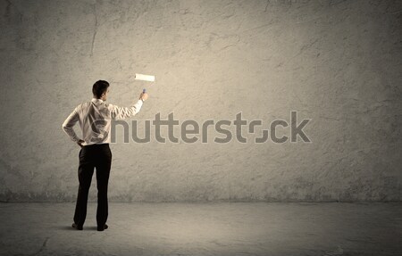 Salesman with roller standing at empty wall Stock photo © ra2studio