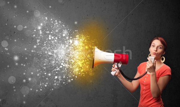 Woman shouting into megaphone and glowing energy particles explode concept Stock photo © ra2studio