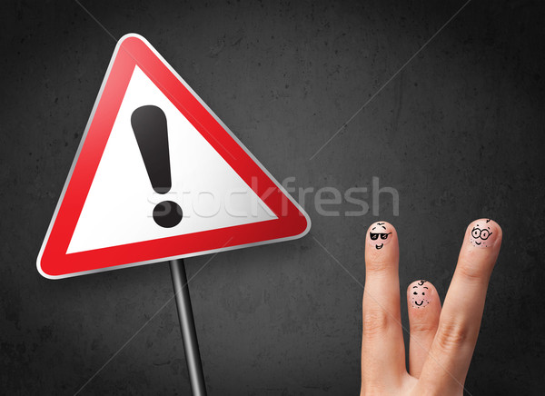 Happy cheerful smiley fingers looking at triangle warning sign with exclamation mark Stock photo © ra2studio