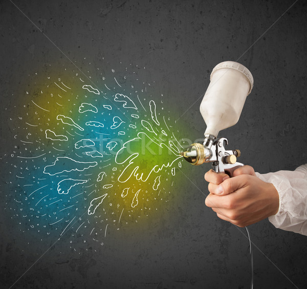 Worker with airbrush gun paints colorful lines and splashes Stock photo © ra2studio
