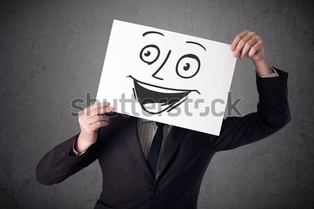 Businessman holding a cardboard with smiley face on it in front  Stock photo © ra2studio