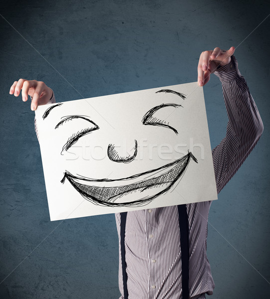 Businessman holding a paper with smiley face in front of his hea Stock photo © ra2studio