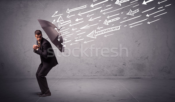 Business man standing with umbrella and drawn arrows hitting him Stock photo © ra2studio