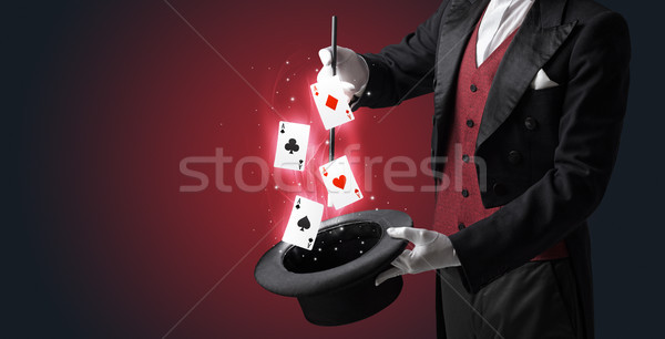 Stock photo: Magician making trick with wand and playing cards