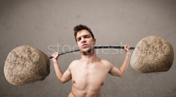 Stock photo: skinny guy lifting large rock stone weights