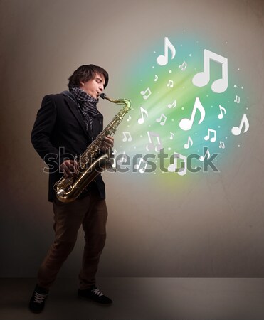 Young musician playing on saxophone while musical notes explodin Stock photo © ra2studio