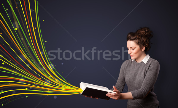 Pretty young woman reading a book while colorful lines are comin Stock photo © ra2studio