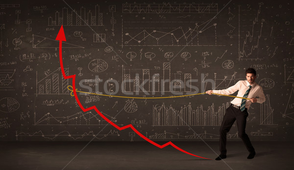 Stock photo: Businessman pulling a red arrow upright with a rope 