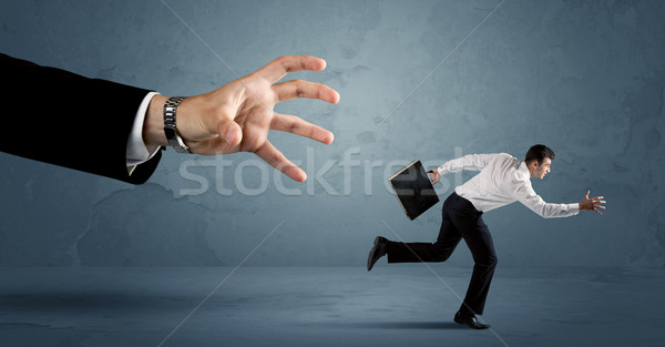 Stock photo: Business man running away from a huge hand concept