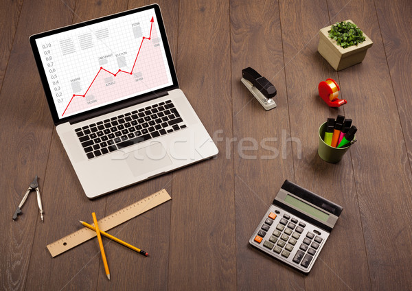 Computer desk with laptop and red arrow chart in screen Stock photo © ra2studio