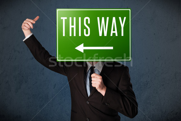 Businessman holding a direction sign Stock photo © ra2studio
