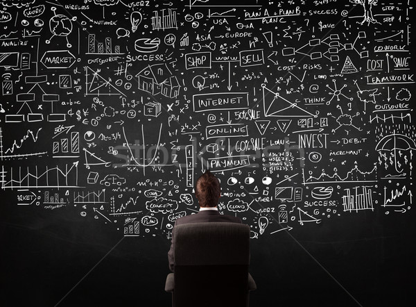 Businessman sitting in front of a blackboard with charts Stock photo © ra2studio