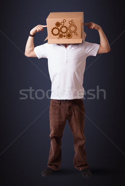 Young man gesturing with a cardboard box on his head with spur w Stock photo © ra2studio