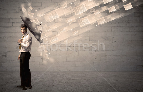 Business man protecting with umbrella against wind of papers Stock photo © ra2studio