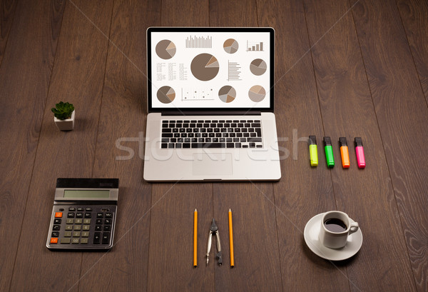 Stock photo: Pie chart graph icons on laptop screen with office accessories 