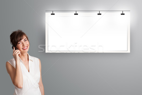 Stock photo: beautiful young woman standing next to a modern copy space and making phone call