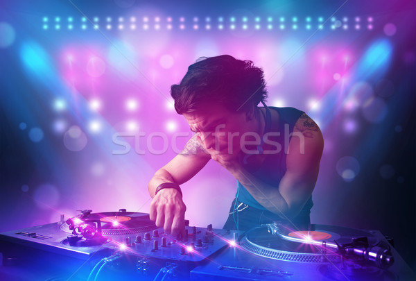 Stock photo: Disc jockey mixing music on turntables on stage with lights and 