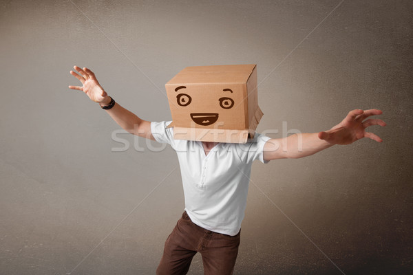 Young man gesturing with a cardboard box on his head with smiley Stock photo © ra2studio