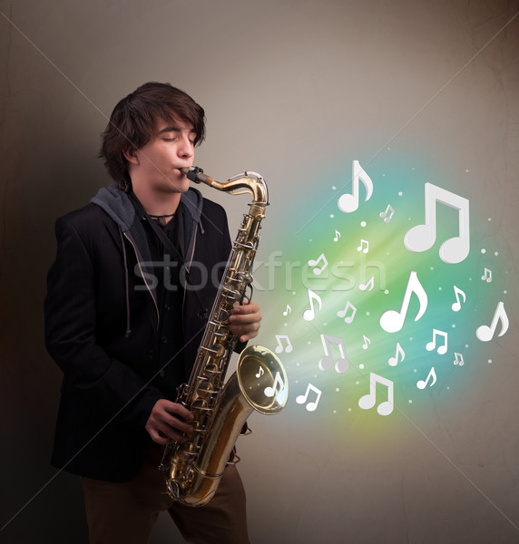 Young musician playing on saxophone while musical notes explodin Stock photo © ra2studio