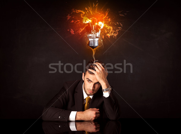 Businessman sitting under a blowing idea bulb Stock photo © ra2studio