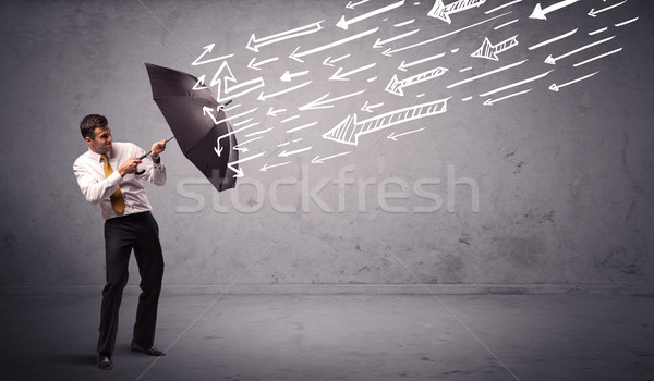 Stock photo: Business man standing with umbrella and drawn arrows hitting him