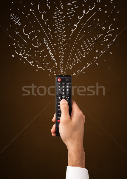 Hand with remote control and curly lines Stock photo © ra2studio