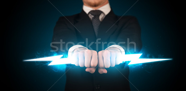 Business man holding glowing lightning bolt in his hands Stock photo © ra2studio