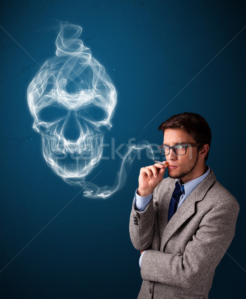 Stock photo: Young man smoking dangerous cigarette with toxic skull smoke 