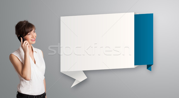 Stock photo: pretty young woman standing next to modern origami copy space and making phone call