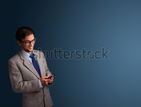 Stock photo: Young man standing and typing on her phone with copy space