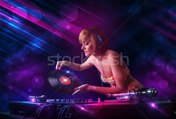 Young DJ playing on turntables with color light effects Stock photo © ra2studio
