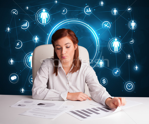 Businesswoman sitting at desk with social network icons Stock photo © ra2studio