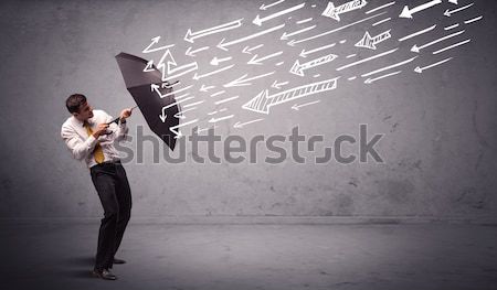 Business man standing with umbrella and drawn arrows hitting him Stock photo © ra2studio