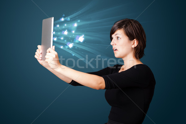 Stock photo: Young business woman looking at modern tablet with abstract lights and social icons