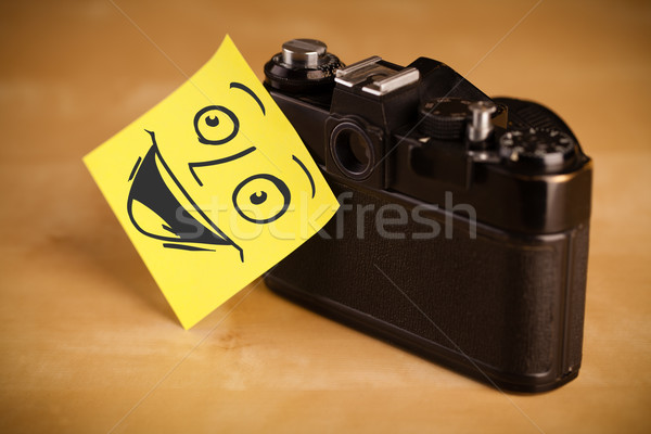 Stock photo: Post-it note with smiley face sticked on photo camera