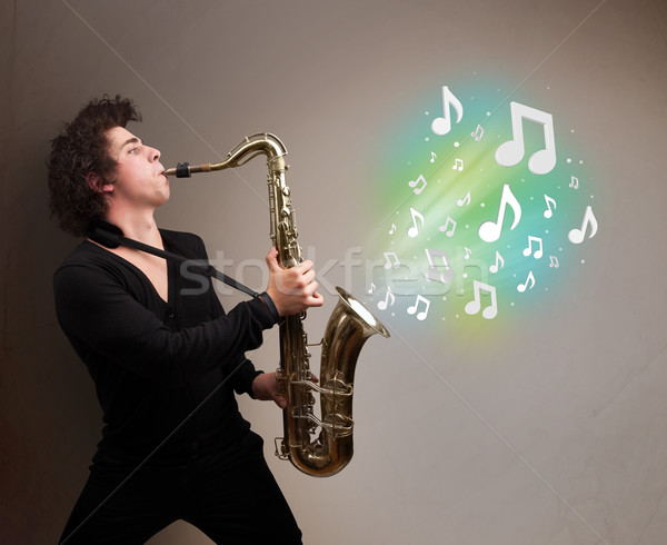 Young musician playing on saxophone while musical notes explodin Stock photo © ra2studio