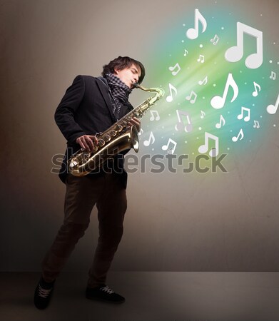 Handsome musician playing on saxophone with musical notes Stock photo © ra2studio