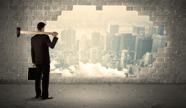 Stock photo: Business man hitting wall with hammer on city view