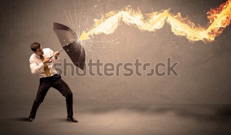 Business man defending himself from a fire arrow with an umbrell Stock photo © ra2studio