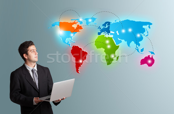 young man holding a laptop and presenting colorful world map Stock photo © ra2studio