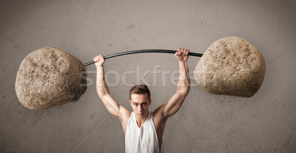 Stock photo: muscular man lifting large rock stone weights