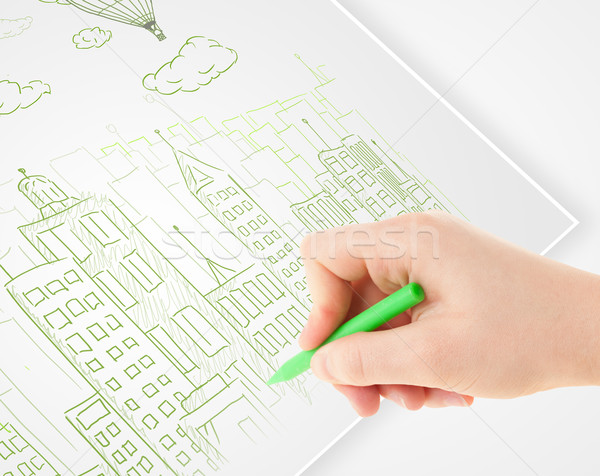 A person drawing sketch of a city with balloons and clouds on a plain paper
 Stock photo © ra2studio
