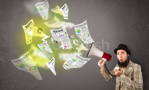 Stock photo: Guy yelling into loudspeaker and newspapers fly out
