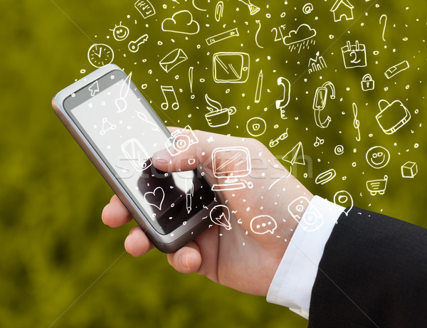 Stock photo: Hand holding smartphone with hand drawn media icons and symbols