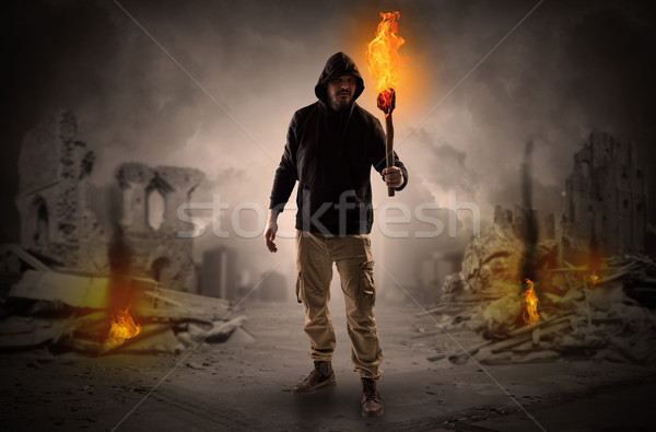 Man coming with burning flambeau at a catastrophe scene concept Stock photo © ra2studio
