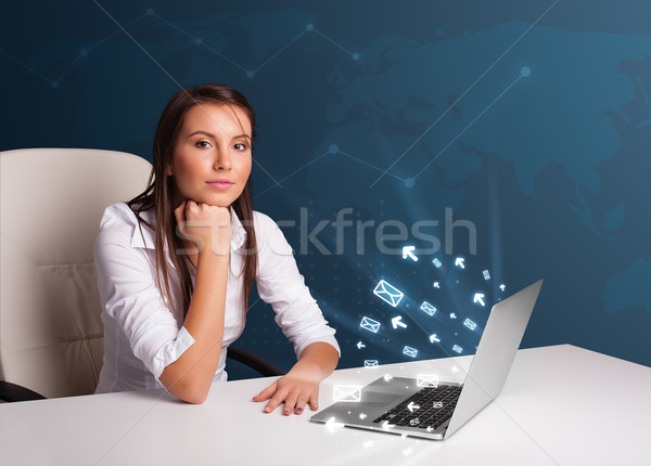 Young lady sitting at dest and typing on laptop with message ico Stock photo © ra2studio